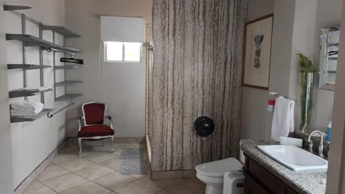 ein Badezimmer mit einem roten Stuhl neben einem WC in der Unterkunft Panoramic Penthouse Downtown (Free Parking) in Tijuana