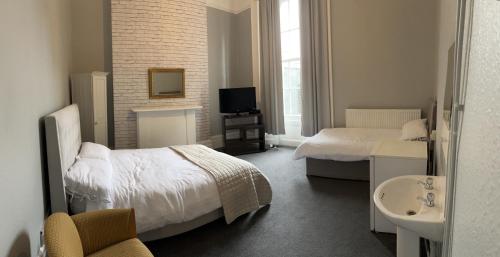 a bedroom with two beds and a sink and a television at Stay in Kings Cross in London