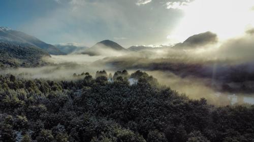 z góry widok na mglistą dolinę z drzewami w obiekcie Peuma Lodge Patagonia w mieście Futaleufú