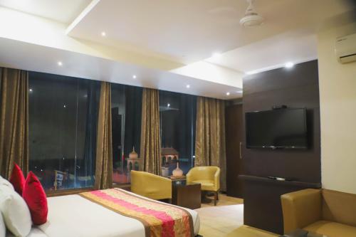 a hotel room with a bed and a flat screen tv at Hotel Central Palace in Dehradun
