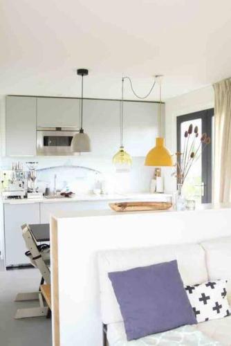 a kitchen with a white counter top and a table at Mooie woonboot op eiland, kachel, natuur, sloep! in Grou