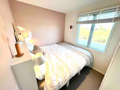 a small bedroom with a bed and a window at Mooie woonboot op eiland, kachel, natuur, sloep! in Grou