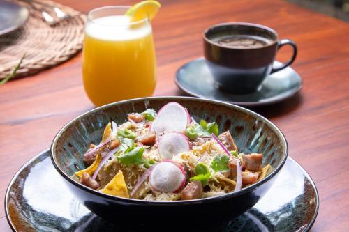 a bowl of food on a table with a cup of orange juice at Oriundo Luxury Nature Villas in Valladolid
