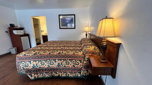 a bedroom with a bed and a lamp on a table at Pine Cone Motel in Willits