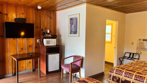a bedroom with a bed and a desk and a microwave at Pine Cone Motel in Willits