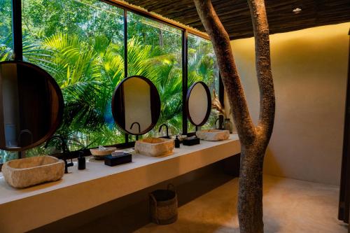 a bathroom with two sinks and mirrors in front of a window at Oriundo Luxury Nature Villas in Valladolid