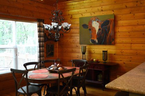 a dining room with a table and a painting of a cow at Moss Haven Cabin - Peaceful Blowing Rock Getaway in Blowing Rock
