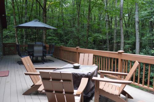 a deck with a table and chairs and an umbrella at Moss Haven Cabin - Peaceful Blowing Rock Getaway in Blowing Rock