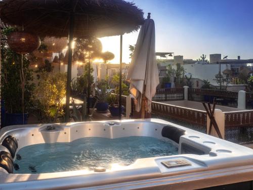a hot tub on a balcony with an umbrella at Riad Dar El Médina - Heated Swimming pool, jacuzzi & Spa in Marrakech