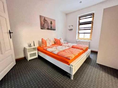 a bedroom with a bed with orange sheets and a window at Ferienwohnungen Otto in Sassnitz