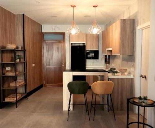 a kitchen with wooden cabinets and two chairs and a table at Alojamiento Turístico "La Condesa Carmen" in Manzanares