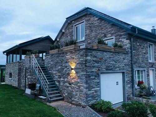a stone house with a staircase on the side of it at PEGASUS I - 2 chambres de luxe, cuisine, salon, 2 terrasses et sauna in Vielsalm