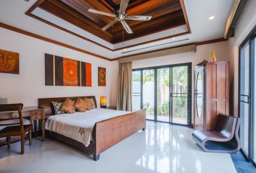 Schlafzimmer mit einem Bett, einem Schreibtisch und einem Fenster in der Unterkunft Lotus Pool Villa in Rawai Beach