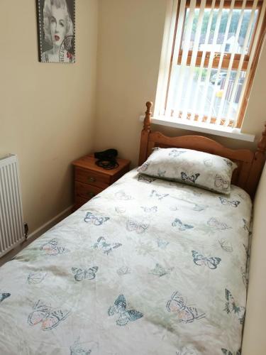 um quarto com uma cama com uma colcha com borboletas em 3 bedroom house em Barrow in Furness