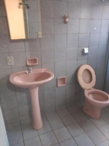 uma casa de banho com um WC cor-de-rosa e um lavatório. em Kitnets para temporada em Uberaba