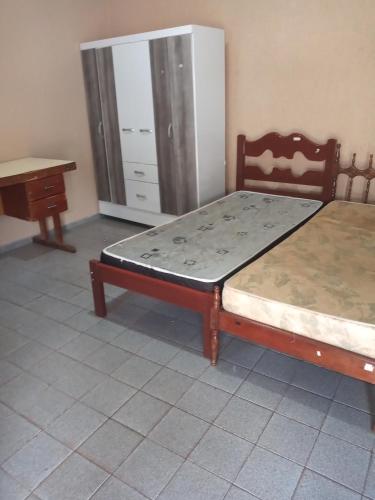 um quarto com 2 camas, uma mesa e uma cómoda em Kitnets para temporada em Uberaba