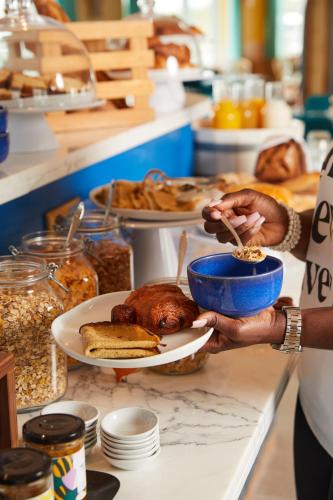 a person holding a plate with a turkey on a counter at Hotel Indigo Bordeaux Centre Chartrons by IHG in Bordeaux