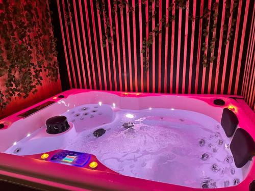 eine rosa Badewanne mit Beleuchtung in einem Zimmer in der Unterkunft Love room Cocon Sri-Yani sauna jacuzzi in Esmans