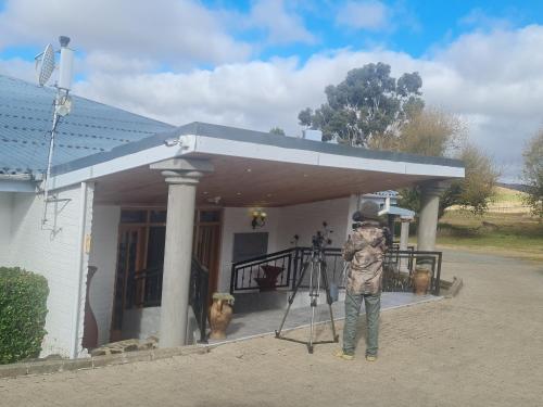 a man standing in front of a house with a camera at mountain shadows hotel in Elliot