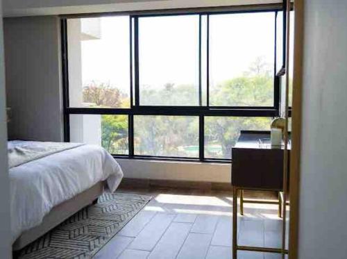 a bedroom with a bed and a desk and a window at Elegant-comfortable space-self checkin & FREE WIFI in Pretoria