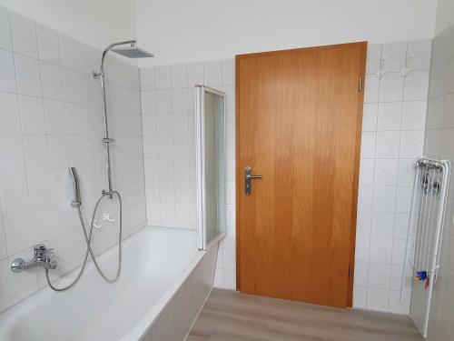 a bathroom with a shower with a tub and a wooden door at Ferienwohnungen direkt am See in Ventschow