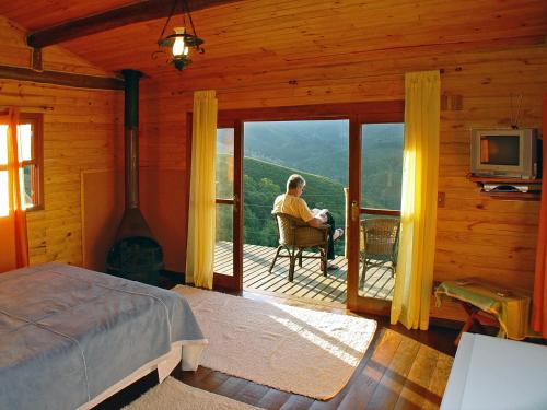 a man sitting in a chair on the porch of a cabin at Cabana Vista Maravilhosa in Visconde De Maua