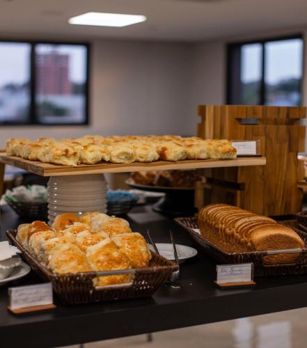 a bakery with several trays of bread and pastries at Comfort Hotel Presidente Prudente in Presidente Prudente