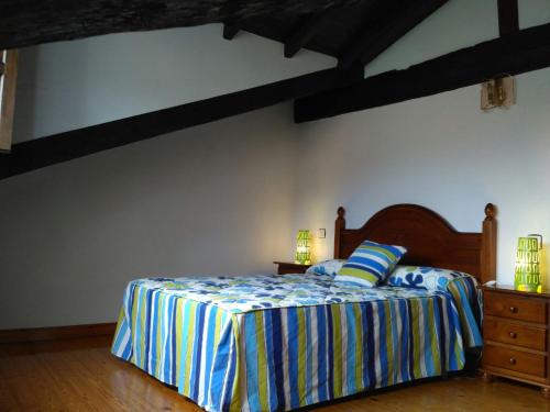 um quarto com uma cama com um edredão listrado em El Coteru em Caviedes