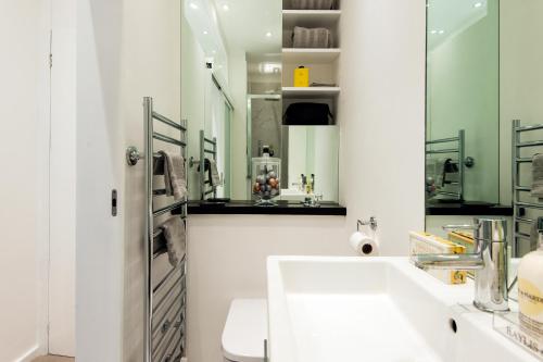 a white bathroom with a sink and a mirror at Welcome London Seven Dials in London