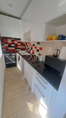 a kitchen with red and white tiles on the wall at Hortenzia Apartman in Tab