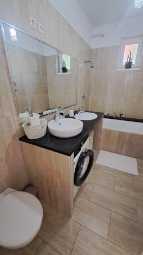 a bathroom with two sinks and a toilet and a tub at Hortenzia Apartman in Tab