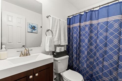 a bathroom with a toilet and a blue shower curtain at Divine Cargo in San Antonio