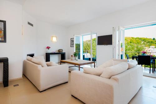 a living room with two white couches and a table at Villa Marceline in Prvić Luka