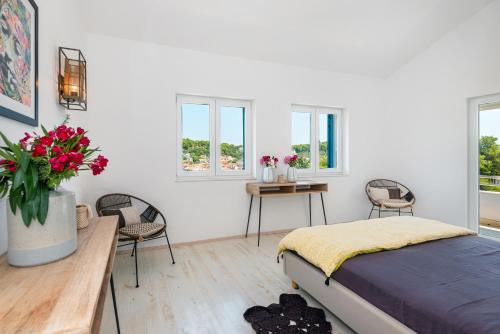 a bedroom with a bed and two chairs and windows at Villa Marceline in Prvić Luka