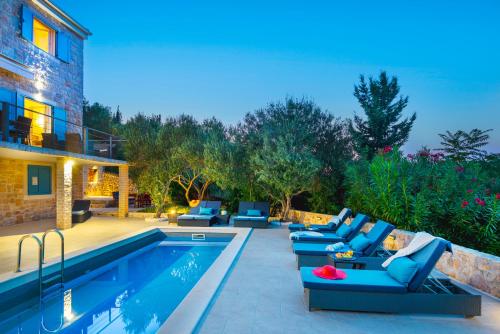 a patio with blue furniture next to a swimming pool at Villa Marceline in Prvić Luka