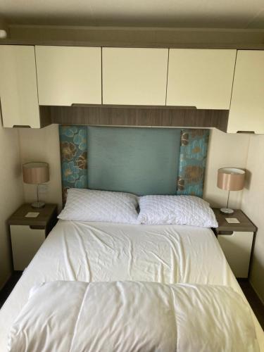 a bedroom with a bed with white cabinets and two lamps at Lyons Robin Hood SEASCAPE in Meliden