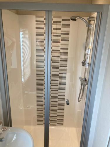 a shower with a glass door next to a sink at Lyons Robin Hood SEASCAPE in Meliden