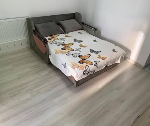 a bed with a blanket with butterflies on it at Lovely 1-room apartment in Popeşti-Leordeni