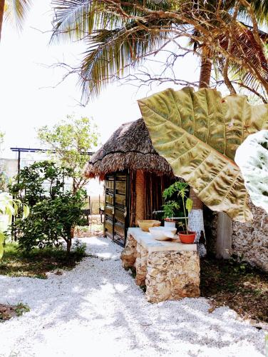 a small hut with a palm tree in front of it at Hotel y Museo Aldea Maya Toktli Orígenes - Casa Maya Toh - Alberca, Wifi Starlink, Tour Museo in Izamal