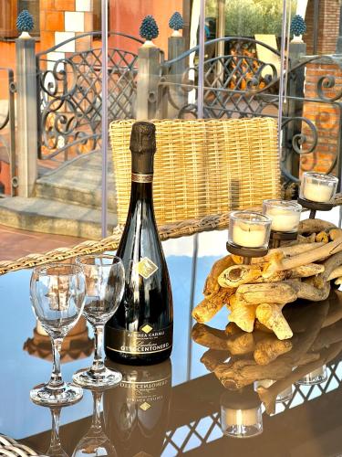 una botella de vino y copas de vino en una mesa en Terre Villa Katia en Santa Maria di Licodia