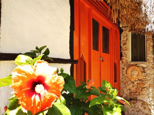 an orange door with a flower in front of a house at Hotel y Museo Aldea Maya Toktli Orígenes - Casa Maya Toh - Alberca, Wifi Starlink, Tour Museo in Izamal