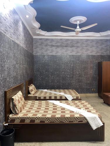 a bedroom with two beds and a ceiling fan at Jinnah inn Guest House in Karachi