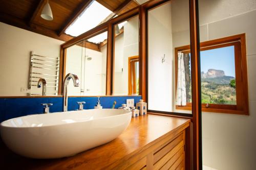 a large white sink in a bathroom with a window at Chalé Leopoldo-Nas Nuvens in São Bento do Sapucaí