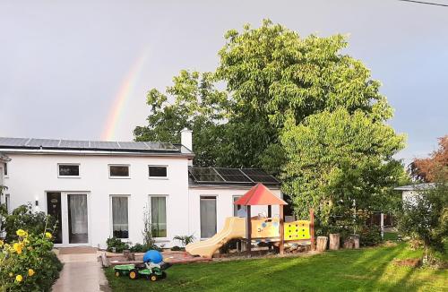 a house with a playground and a rainbow in the background at Chalet im Spiel- und Obstgarten in Keidelheim