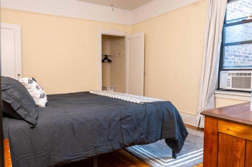 a bedroom with a bed with a black comforter and a window at Hoboken Haven – Heart of town! in Hoboken