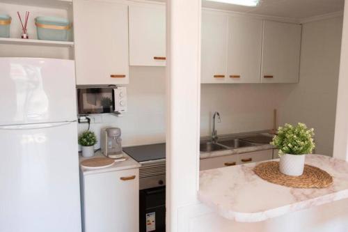 a kitchen with white cabinets and a white refrigerator at Florazar 2, 1a línea, piscina. in Cullera