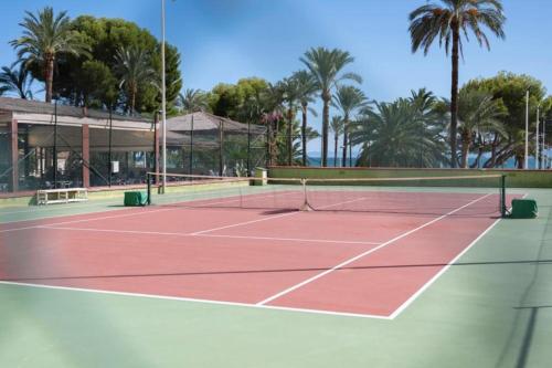 a tennis court with palm trees in the background at Florazar 2, 1a línea, piscina. in Cullera
