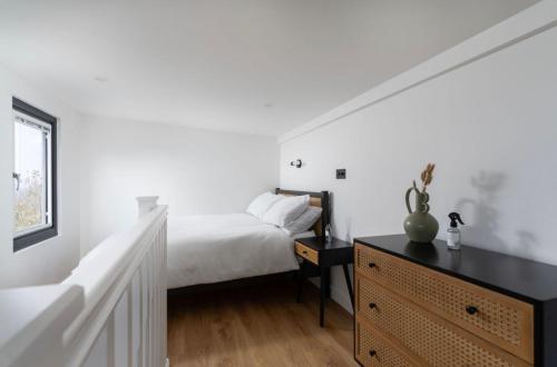 um quarto branco com uma cama e uma cómoda em Lulla Lodge em Lower Boscaswell
