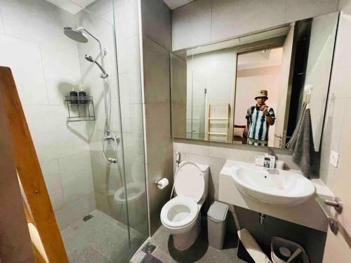 a man taking a picture of a bathroom with a toilet and sink at [300m to PRJ] Expo Friendly 2BR in Jakarta