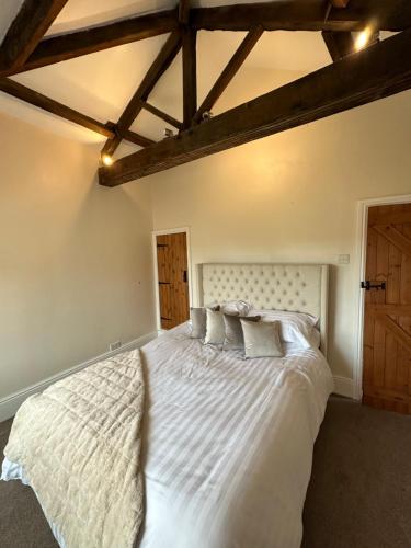 Schlafzimmer mit einem großen weißen Bett und Holzdecken in der Unterkunft Sugar Plum Cottage in Conisbrough